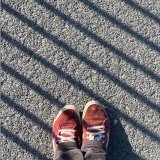 Schuhe auf Asphalt. Grafisch mit schr&auml;gen Linien durch Schatten